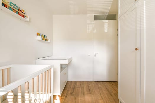 A bright and airy nursery featuring a stylish crib, neutral color scheme, and natural wood flooring. The space is designed for comfort and functionality.