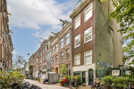 A picturesque view of a street in Amsterdam, featuring charming buildings, lush trees, and bicycles parked along the path, capturing the essence of Dutch architecture.