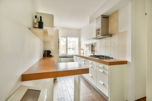 A sleek and modern kitchen featuring a minimalist design. Clean lines, light colors, and a spacious layout create a functional cooking area, complemented by large windows.