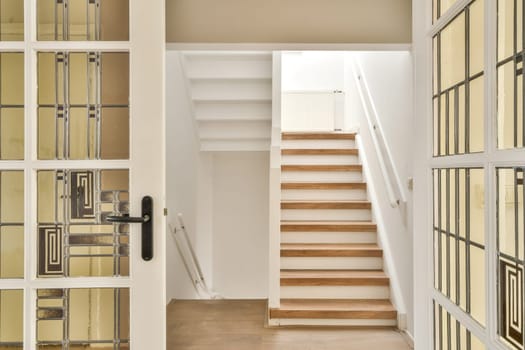 A stylish view of a modern staircase through decorative glass doors, showcasing a bright and inviting interior space with a minimalist design.