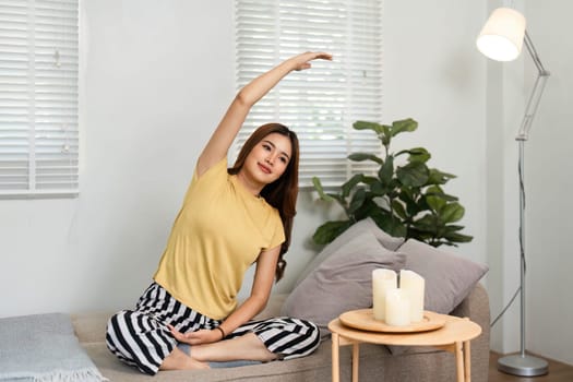 A woman engages in her calming morning routine by stretching at home, focusing on her health and mental clarity while enjoying a peaceful space.