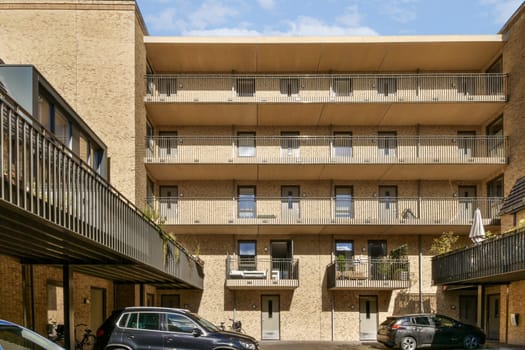 A contemporary apartment complex showcasing a minimalist architectural design with multiple balconies and large windows, surrounded by greenery.