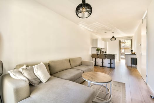 A stylish modern interior featuring a cozy living area with a gray sofa, round coffee table, and contemporary lighting, showcasing open space and natural light.