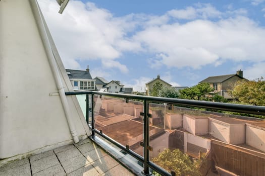 A beautiful view from a balcony showcasing modern architecture and greenery under a bright blue sky with fluffy clouds.