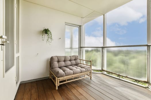 A serene balcony featuring a comfortable seating area surrounded by glass, offering a view of nature and a calm atmosphere.