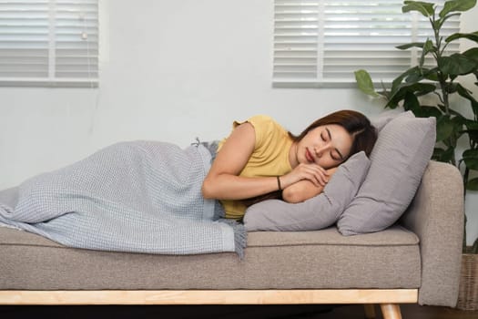 A young woman is sleeping soundly on a soft couch in a bright room, embodying the essence of a calm morning routine and relaxation.