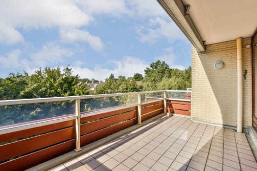 A spacious balcony showcasing a vibrant view of lush green trees and a clear blue sky, ideal for relaxation and outdoor enjoyment.