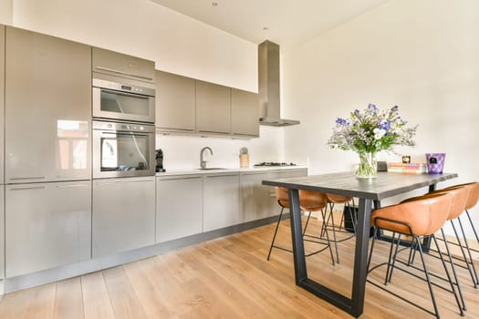 A sleek and contemporary kitchen interior featuring glossy cabinets, a dining table, and a vibrant floral arrangement that adds color and freshness.