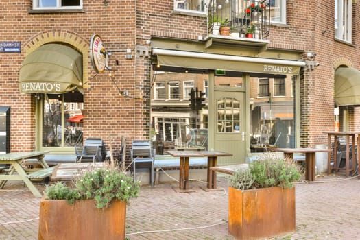 A delightful outdoor cafe featuring cozy seating and vibrant plants, set against a backdrop of historic brick architecture. Perfect for leisurely dining and socializing.
