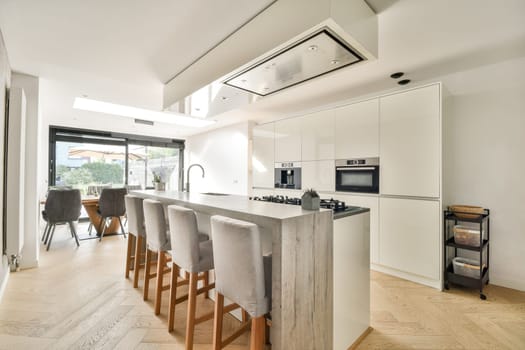 A sleek modern kitchen featuring minimalist cabinetry, elegant seating, and ample natural light from large windows, perfect for contemporary living.