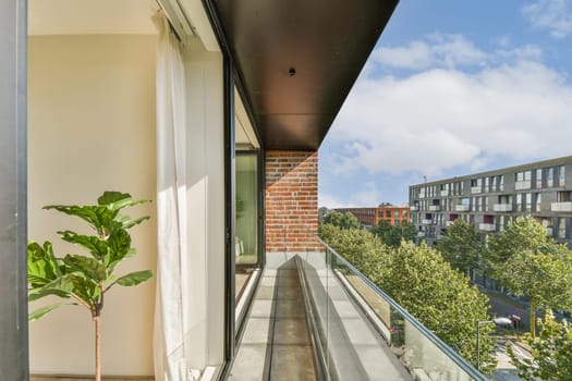 A stylish balcony featuring greenery and a view of contemporary buildings under a bright sky, ideal for urban living aesthetics.