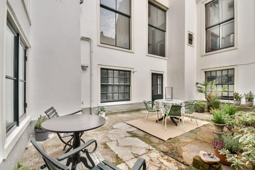A serene courtyard featuring modern architecture, tables, chairs, and lush plants, providing a perfect spot for relaxation and gatherings.