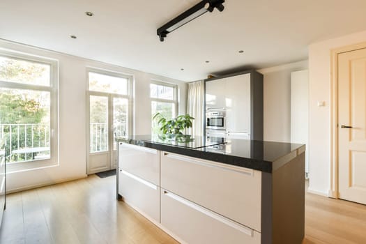 A sleek and contemporary kitchen featuring minimalistic cabinetry, large windows for natural light, and a stylish layout that combines functionality with aesthetic appeal.