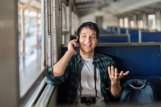 A young traveler sits comfortably on a train, engaged in a phone conversation, with an excited smile, ready for adventure.