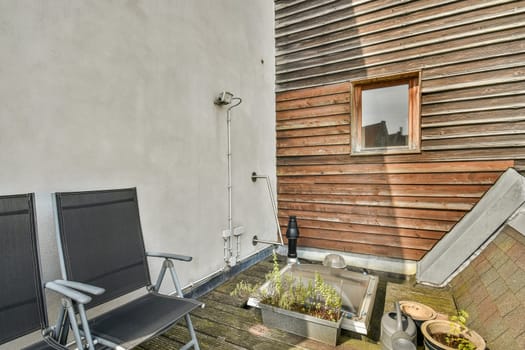 A serene outdoor patio featuring wooden walls, two chairs, and planters, perfect for relaxation and enjoying nature.