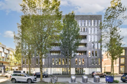 A sleek modern residential building features large windows and is framed by several trees, showcasing urban architecture harmonizing with nature.