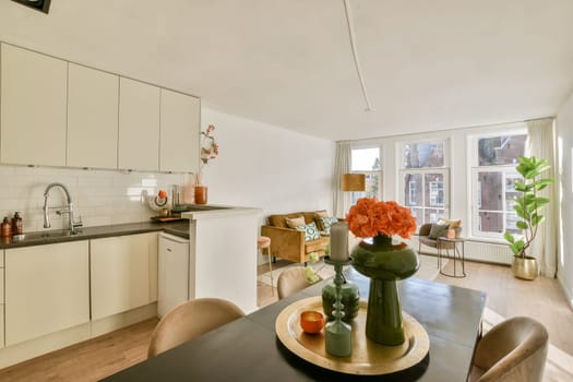 A beautifully arranged living space featuring a kitchen, plants, and a warm ambiance, showcasing modern interior design elements and natural light.