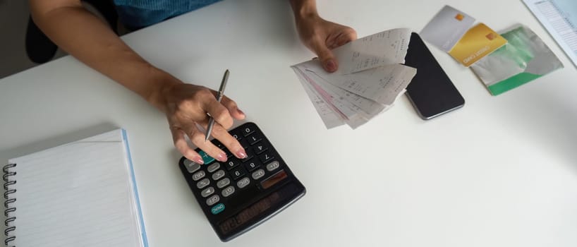 An attentive individual is managing their finances, holding multiple receipts, and calculating bills to maintain a stable budget.