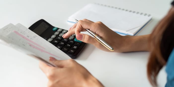 A person is carefully reviewing bills and calculating expenses, showcasing a proactive approach to personal finance and budgeting.