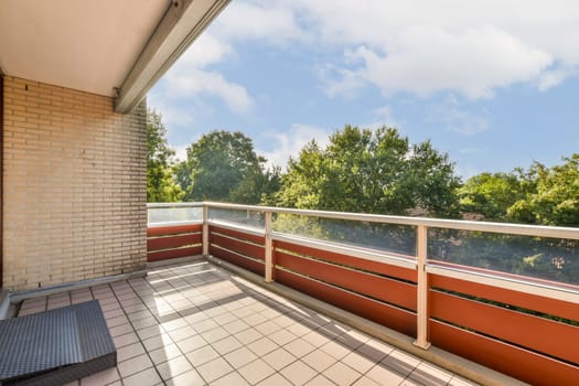 A stylish balcony features a spacious area with tiled flooring surrounded by lush green trees under a bright sky, creating a tranquil outdoor space.