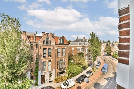View of charming historic buildings along a winding road, surrounded by lush greenery under a clear blue sky, showcasing a vibrant urban environment.