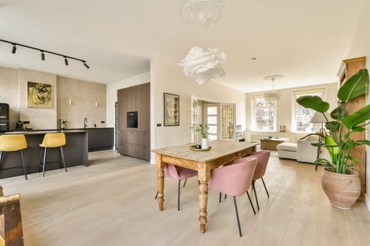 Bright and airy open-concept interior featuring a sleek kitchen, dining area, and comfortable living space, adorned with plants and contemporary decor.