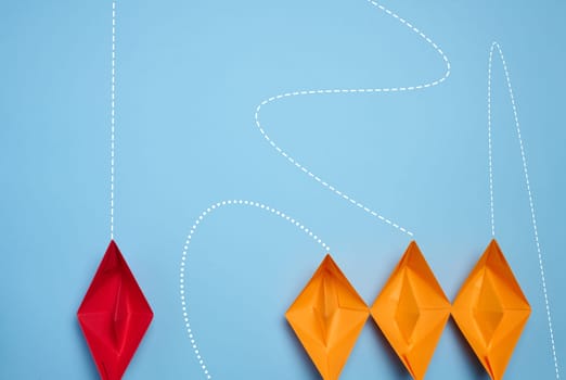 Paper boats on a blue background, representing the concept of competition in business, teamwork, and innovative approaches for achieving goals