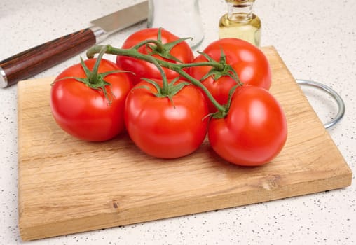 Red ripe tomatoes on a green branch on a white table, healthy vegetable