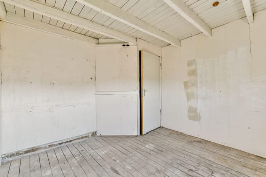 A vacant interior space featuring wooden flooring, white walls, and a simple door. The absence of furniture gives a sense of openness and possibility.