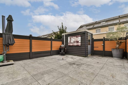 The image showcases a stylish modern patio surrounded by wooden fencing and greenery, highlighting contemporary architecture and a cozy outdoor space.