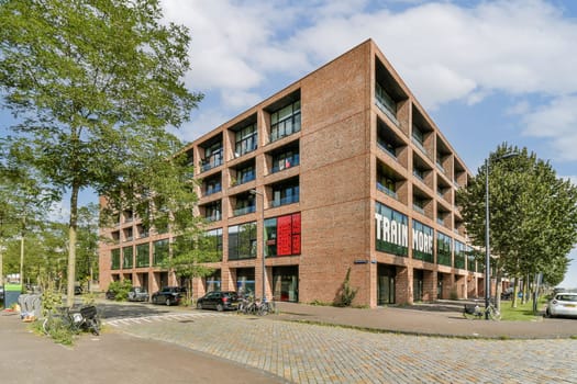 A striking modern building featuring unique brickwork alongside lush trees and greenery, showcasing contemporary urban design.