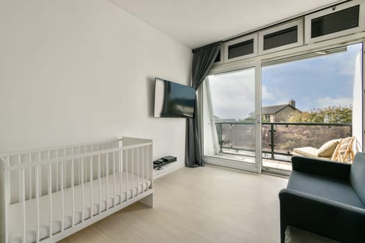 A bright and airy modern interior featuring a crib, sleek furnishings, and large windows that provide a view of the outdoors, enhancing the peaceful atmosphere.