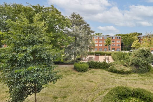 Lush greenery surrounds well-maintained pathways in an urban park setting, providing a tranquil atmosphere amidst city life, featuring trees, grass, and benches for relaxation.
