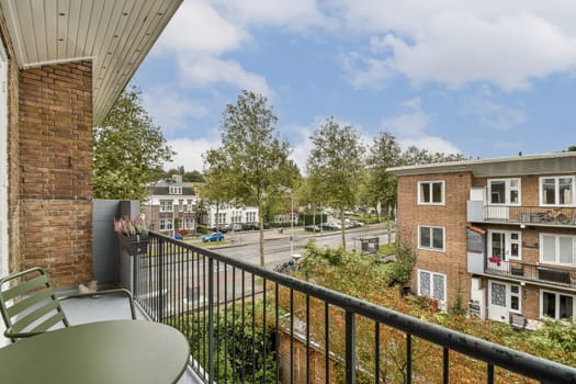 A vibrant urban scene showcasing a balcony overlooking trees lining the street and modern buildings, capturing a serene atmosphere in the city.