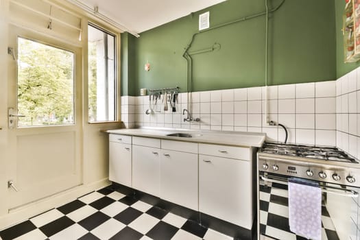 A sleek kitchen featuring a green wall, checkered flooring, and modern appliances. The spacious layout enhances functionality and style.