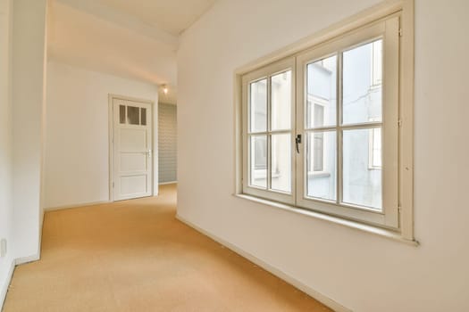 A spacious indoor area featuring light walls, a large window, and a modern aesthetic. The natural light enhances the minimalist design and ambiance.