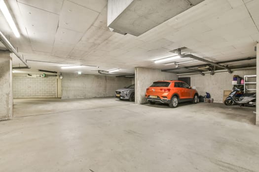 A spacious and well-lit underground parking garage featuring two parked vehicles. The modern architecture emphasizes clean lines and functionality.