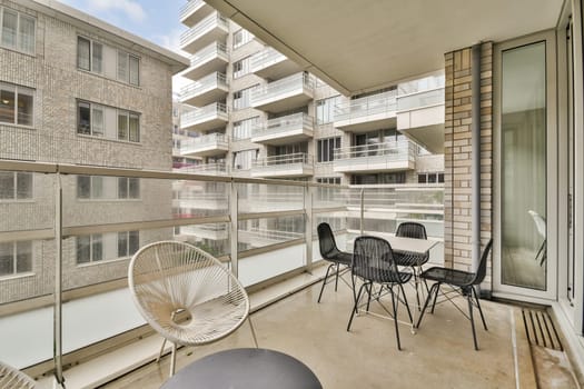 A stylish balcony showcasing contemporary architecture and city living, featuring glass railings and minimalist furniture under a clear sky.
