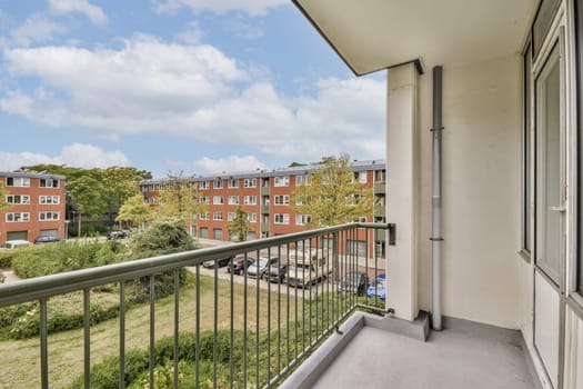 A spacious balcony overlooking a vibrant residential area with greenery and blue skies, perfect for relaxation and enjoying the outdoors.