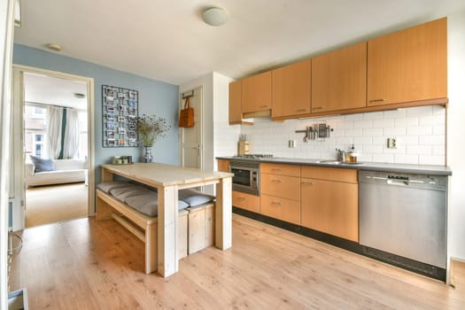 A contemporary kitchen featuring wooden cabinetry, modern appliances, and a cozy dining area, illuminated by natural light from nearby windows.