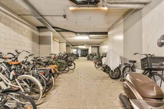A spacious and well-organized bicycle parking area featuring numerous parked bikes, illuminated by overhead lights for visibility and convenience.