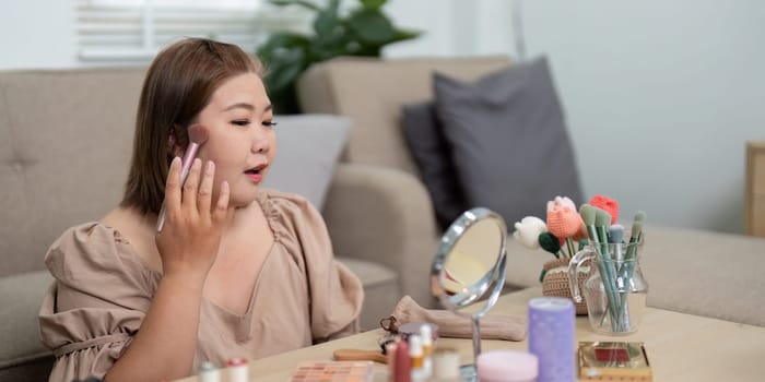 Focusing on her look, she uses professional brushes to apply blush, enhancing her cheeks as she prepares for the day.