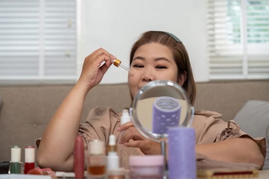 In a cozy setting, a woman applies serum while admiring her reflection in a mirror, emphasizing her daily skincare practices and the significance of nurturing her skin.