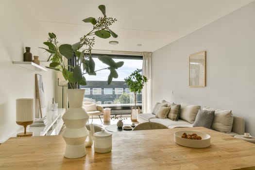 A stylish living room showcasing minimalist decor with a focus on natural elements. The space features plants, soft furnishings, and a spacious layout that promotes tranquility.