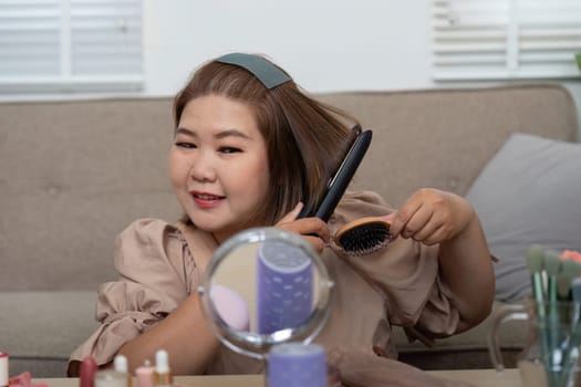 This woman enjoys her grooming session, brushing her hair to perfection and showcasing confidence in her beauty regimen.