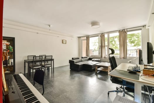 A stylish and spacious living room featuring natural light, modern furniture, and a creative workspace, perfect for relaxation and productivity.