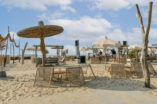 A serene beachside cafe featuring umbrellas, lounge chairs, and beautiful sandy surroundings, perfect for a relaxing day by the ocean.