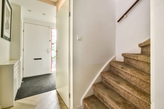 A contemporary staircase leading to an entrance, showcasing clean lines and a minimalist design with natural light streaming in.