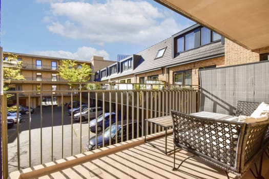 A stylish balcony showcasing modern architecture with a view of an urban courtyard and parked cars. Natural light highlights the contemporary design elements.