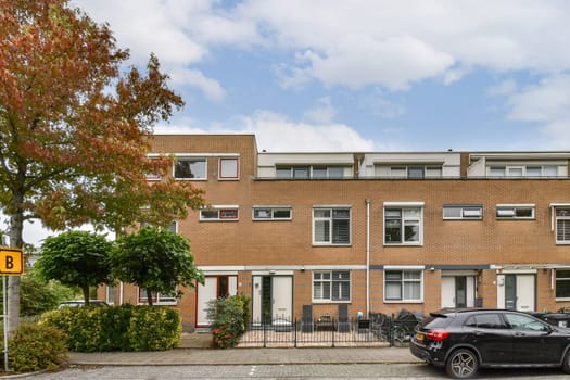 A modern residential building featuring a well-maintained facade and lush greenery in front, creating an inviting atmosphere. Perfect for showcasing contemporary architecture.
